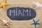 Handwritten word MIAMI written in chalk, among seashells and starfishes