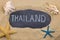 Handwritten word THAILAND written in chalk, among seashells and starfishes