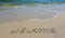 Handwritting inscription welkome word on tropical sandy beach, travel concept card for holidays