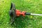 Handy trimmer for mowing grass in garden and courtyard, green meadow on background