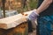 Handy woodcutter prepares larch wood for later processing. Planing wood. Working larch boards with traditional tools. Hand