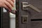 Handyman lubricating door lock with oil indoors, closeup