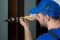 Handyman repair the door lock in the room. Closeup of man repairing the doorknob.