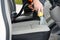 Handyman vacuuming car front textile seat with vacuum cleaner. man cleaning work machine