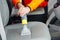 Handyman vacuuming car front textile seat with vacuum cleaner. man cleaning work machine