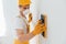 Handyman in yellow uniform and protective mask polishing wall indoors. House renovation conception