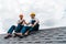 Handymen in helmets holding hands while sitting on rooftop