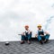 Handymen in helmets and uniform sitting on rooftop