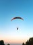 A hang-glider with a motor flies against a blue sky