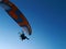 A hang-glider with a motor flies against a blue sky