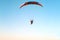 A hang-glider with a motor flies against a blue sky
