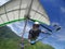 Hang glider pilot soaring the thermal updrafts above green mount