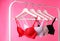 Hangers with beautiful lace bras on rack against background. Stylish underwear