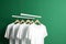 Hangers with blank monocolor t-shirts on green background, neural network generated image
