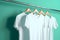 Hangers with blank monocolor t-shirts on turquoise background, neural network generated image