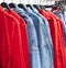 Hangers with comfortable denim clothing in the chain store. Blue denim shirts and jackets, red loose cut shirts.