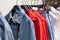 Hangers with comfortable denim clothing in the chain store. Blue denim shirts and jackets, red loose cut shirts.