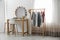 Hangers with stylish clothes on rack and table in makeup room