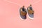 Hanging baby shoes isolated on pink background, baby clothing concept