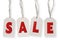 Hanging cardboard tags with word SALE against white background