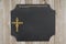 Hanging chalkboard with a gold cross on weathered wood wall