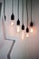 Hanging edison light bulbs on black strings on white wall background