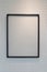 Hanging empty black wooden picture frame on orderly dot or hole wall with orange light form ceiling