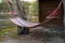 Hanging empty hammock between pine trees in forest for camp and rest
