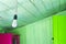 Hanging Energy Saving LED Light Bulb. Walls And Ceiling Decorated With Green Wooden Planks, Opened Green Door And Violet Cupboard