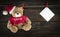 Hanging teddy bear in a christmas hat on a wooden background