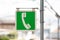 Hanging telephone public payphone sign on a pole. Color green