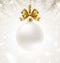 Hanging white Christmas bauble with glitter golden ribbon on a winter snow background. Christmas ball with copy space for your gre