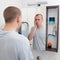 Hangover concept - tired man looking at mirror in bathroom