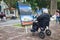 Hanoi, Vietnam - Jan 22, 2016: Old man sitting on wheelchair watches photo at outdoor photo exhibition beside Hoan Kiem lake, cent