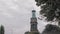 HANOVER, GERMANY - October 2018: Medieval bell tower with a clock and a cross on the dome. And a few green tree branches