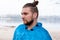 Hansome bearded man with hair bun, sticks and make up looking away