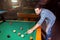 Hansome man playing pool in bar alone