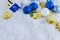 Hanukkah decorations including gelt, sparkly ornaments and a dreidel in snow.