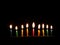 Hanukkah is a Jewish religious holiday of candles. Nine burning candles on dark background. The Feast of Fire and Light