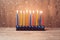 Hanukkah menorah with colorful candles over wooden background