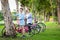 Happiness asian mother and daughter standing near their bicycle in green nature at outdoor park,beautiful smiling child girl and