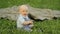 Happiness Baby boy sitting on the grass and playing on a blanket in the garden