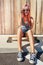 Happiness is contagious. a young woman sitting on her skateboard on a sidewalk.