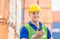 Happiness foreman in hardhat and safety vest talks on two-way radio control loading containers box from cargo