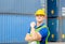 Happiness foreman worker in hardhat show strong arm muscles at containers cargo