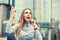 Happiness good news. woman celebrating fists up talking at phone, earphone looking up isolated near corporate business center