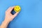 Happiness and positivity concept. Hand holding yellow smiling face in blue background with copy space.