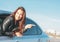 Happpy beautiful charming brunette long hair young asian woman in black leather jacket with key in car window