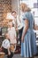 happy 1950s man and kids looking at beautiful woman in blue dress