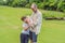 A happy 40-year-old father cradles her newborn with his adult son in a sun-drenched park. Love, family and generations